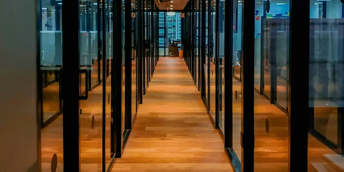 A long hallway with glass panels and a wooden floor